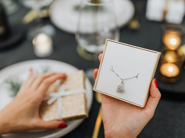 An open box with silver necklace on women hand.