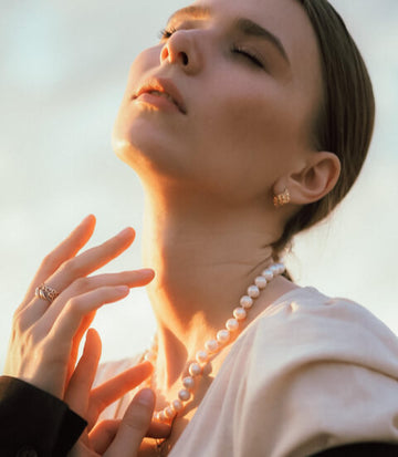 women wear pearl neckalce and gold ring.