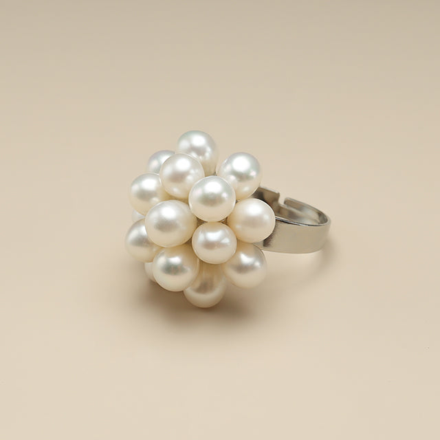 A adjustable pearl ring on beige paper.