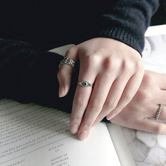 Aesthetic cross rings and evil eye ring on finger.