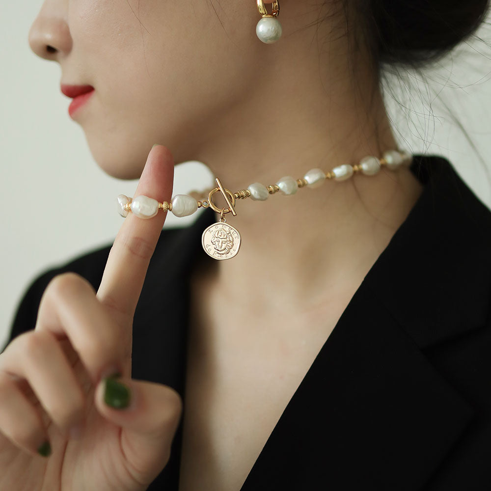 Women in black wear big pearl necklace.