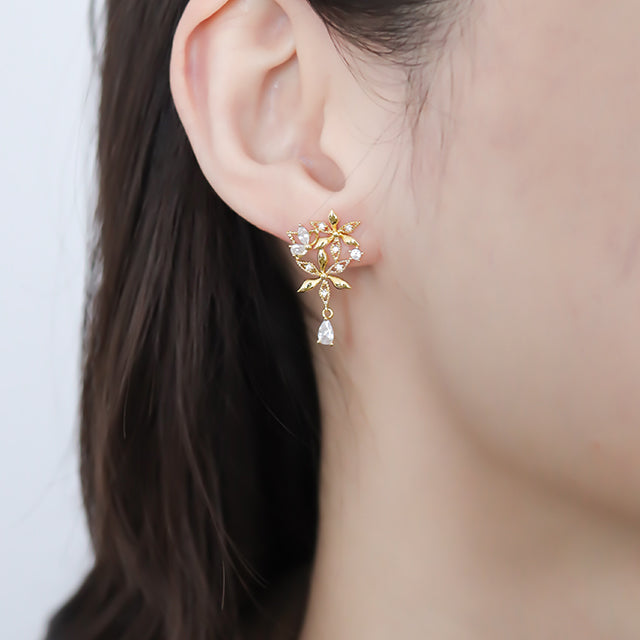 Gold hanging earrings with white diamond on women ear.