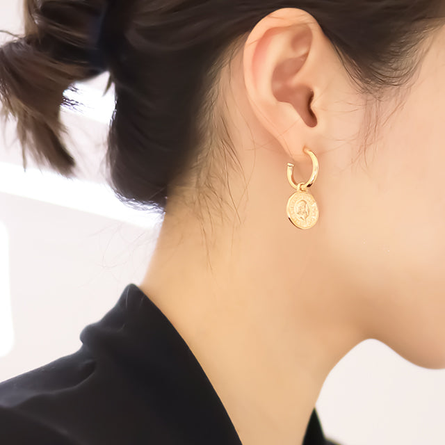 Women in black wear gold huggie earrings.
