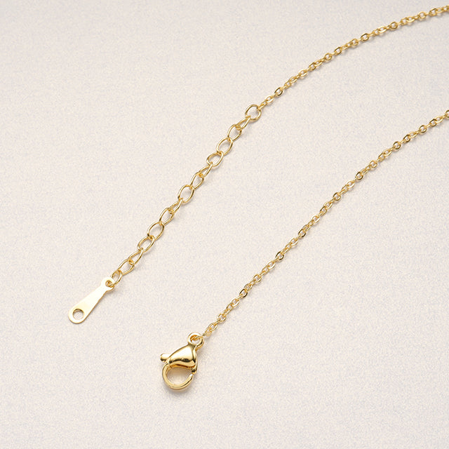 A adjustable gold plated necklace clasp on paper.