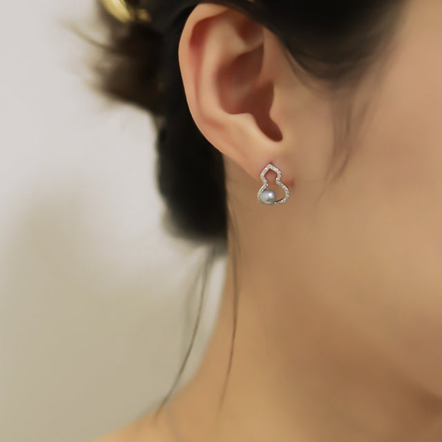 Ladies earrings wih grey pearl on women ear.