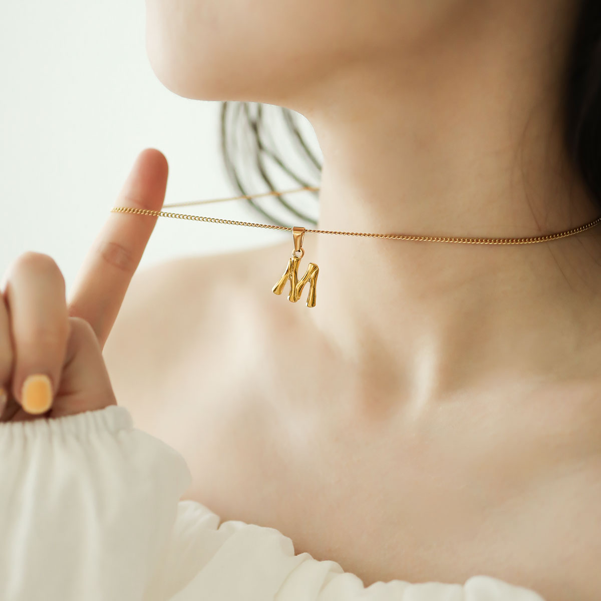 Women wear letter m necklace.