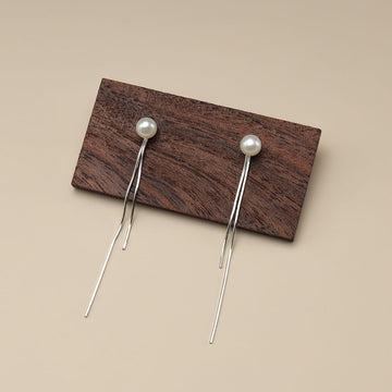 A pair of pearl tassel earrings on wood.