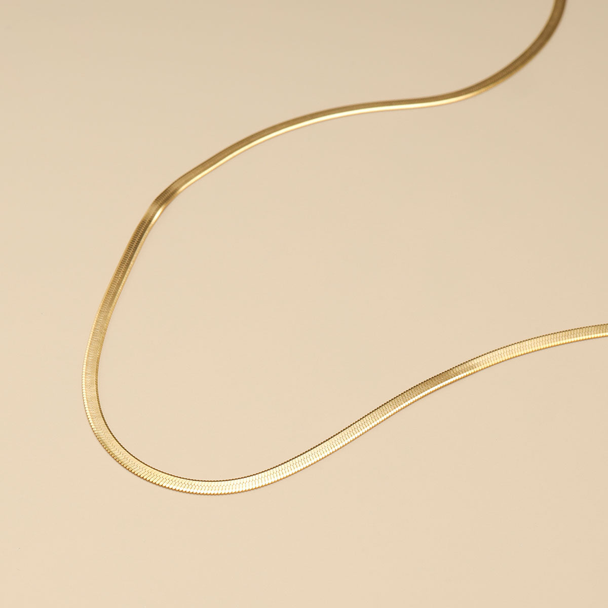 A snake chain necklace in gold.