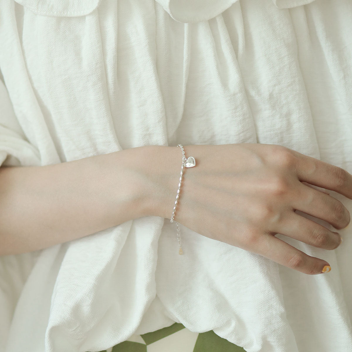 Women in white wear solid silver bracelet.